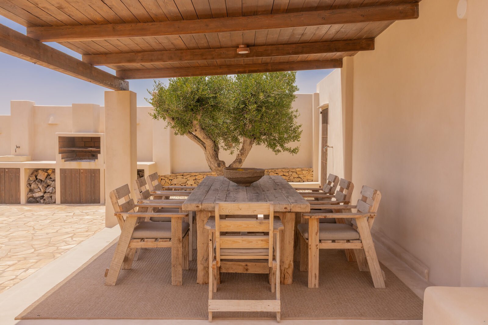 Pérgola con mesa de madera bajo el olivo